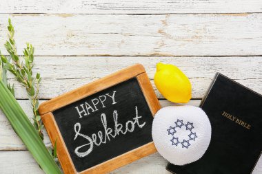 Hafif ahşap zemin üzerinde yazı tahtası ve Sukkot festival sembolleri bulunan kompozisyon