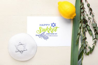 Beyaz ahşap arka planda Sukkot festival sembolleri ve tebrik kartı