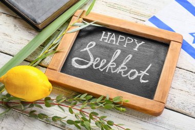 Yazılı tebeşir tahtası Mutlu SUKKOT ve hafif ahşap arka planda festival sembolleri