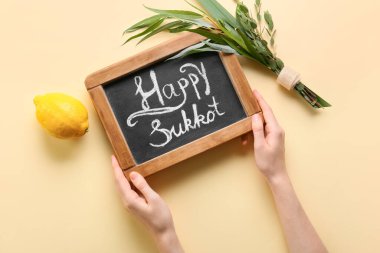 Renk arkaplanında yazı tahtası ve Sukkot festival sembolleri olan eller