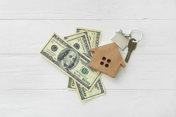 房子的形象 钥匙串和钱在白色木制背景上 — 图库照片