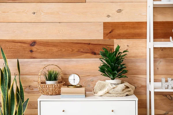 Dekorlu çalar saat ve odadaki çekmecelerin üstündeki bitkiler.