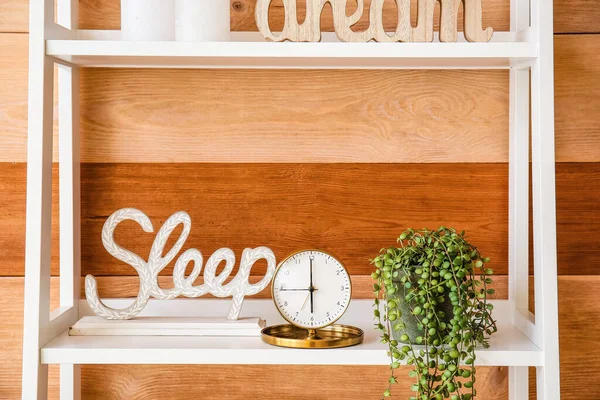 木製の壁の近くの装飾と棚の上のスタイリッシュな目覚まし時計 — ストック写真