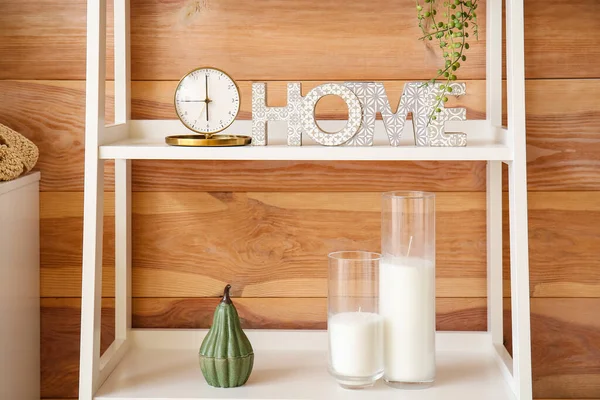 Şık bir odanın içindeki rafta dekoru olan altın alarm.