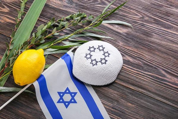 Ahşap zemin üzerinde Sukkot festival sembolleri ve İsrail bayrağı bulunan kompozisyon