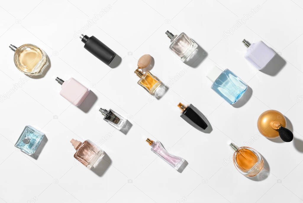 Composition with different bottles of elegant perfumes on white background