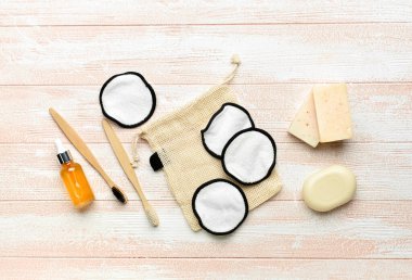 Hafif ahşap arka planda yeniden kullanılabilir pamuk pedler, sabun ve diş fırçaları