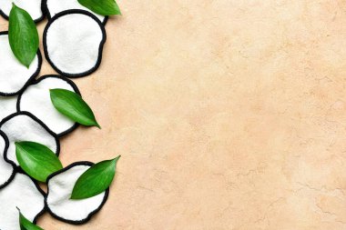 Renk arkaplanında yeniden kullanılabilir pamuk pedleri ve yeşil yapraklar