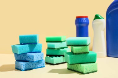 Renkli arka planda farklı temizlik süngerleri ve deterjan şişeleri