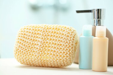 Banyo süngeri ve kozmetik ürünleri banyodaki masada, yakın plan.