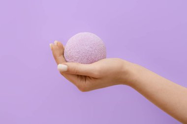 Leylak arka planında banyo bombası tutan kadın, yakın plan.