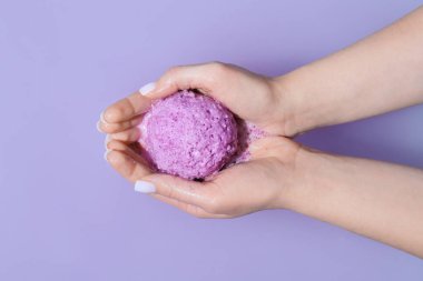 Renkli arka planda eritme banyosu bombası olan kadın eller, yakın plan