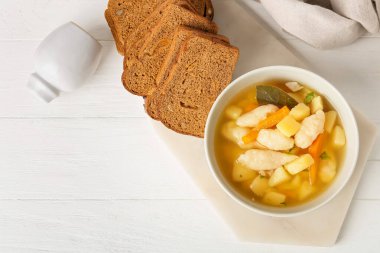 Bir kase lezzetli hamur çorbası ve hafif ahşap arka planda dilimler.