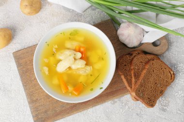 Tahta tahta tahta tahtada bir kase lezzetli hamur çorbası ve hafif arka planda malzemeler.