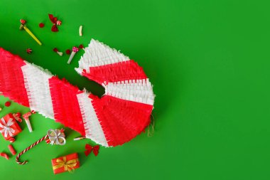 Baston şeklinde Meksika pinyatası ve yeşil arka planda hediyeler.