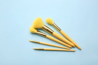 Mavi arkaplanda şık makyaj fırçaları.