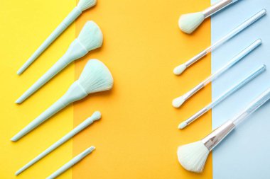 Renkli arkaplanda şık makyaj fırçaları olan kompozisyon