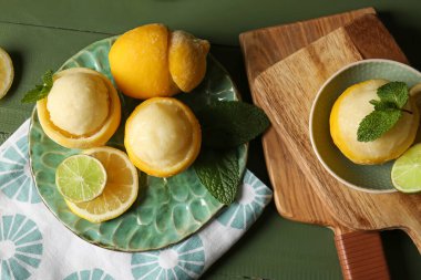 Tabak ve kâse içinde limon kabuklarıyla lezzetli dondurmalar ahşap arka planda.