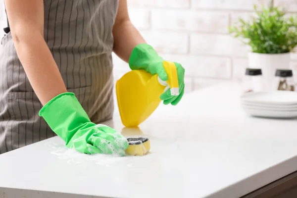 厨房里用海绵和洗涤剂擦桌子的女人 — 图库照片
