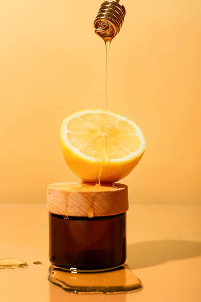 レモンと色の背景に化粧品の瓶に蜂蜜を注ぐ — ストック写真