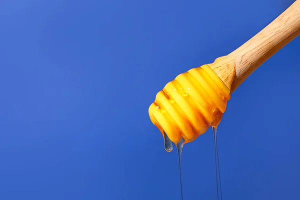 青い背景の上から甘い蜂蜜を注ぐ クローズアップ — ストック写真