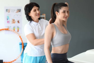 Genç bir kadın rehabilitasyon merkezinde fizyoterapistle terapi görüyor.