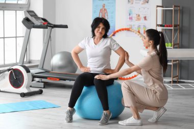 Rehabilitasyon merkezinde fitball ve fizyoterapist eğitimi almış olgun bir kadın.