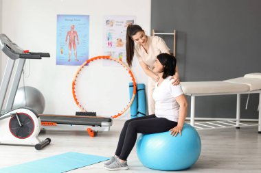 Rehabilitasyon merkezinde fitball ve fizyoterapist eğitimi almış olgun bir kadın.