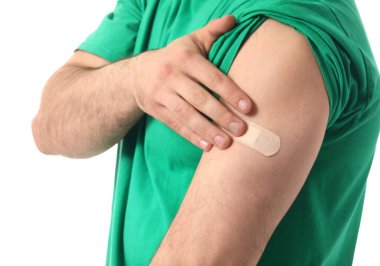 Genç adam beyaz arka planda koluna alçı yapıştırıyor.