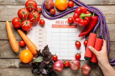 Yemek planı olan sağlıklı ürünler ve ahşap arka planda ip atlama