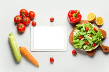 Tablet bilgisayar ve beyaz arkaplanda sağlıklı ürünler