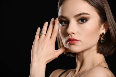 Siyah arka planda güzel manikürlü ve moda aksesuarlı bir kadın.