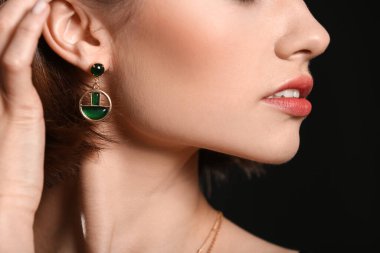 Koyu arkaplanda zarif küpeleri olan zarif bir kadın. Yakın plan.