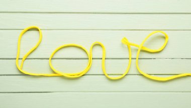 Aşk kelimesi, tahta arka planda ayakkabı dantelinden yapılmıştır.