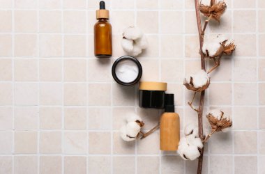 Farklı kozmetik ürünleri ve hafif fayans üzerinde güzel pamuk dalı