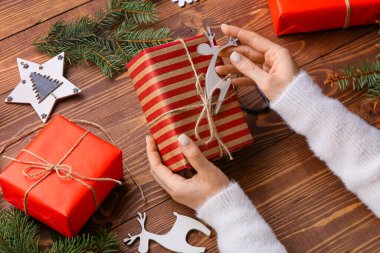 Noel hediyelerini ahşap arka planda süsleyen kadın, yakın plan.