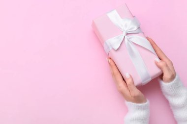 Pembe arka planda hediye kutusu tutan kadın, yakın plan.