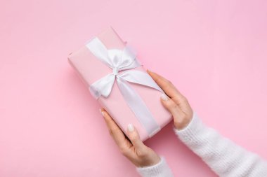 Pembe arka planda hediye kutusu tutan kadın, yakın plan.