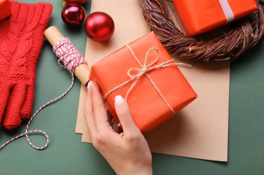 Noel hediyeli kadın eli, renkli arka planda ip ve kağıt çarşaflar, yakın plan