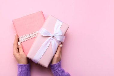 Pembe arka planda hediye kutuları tutan kadın, yakın plan.