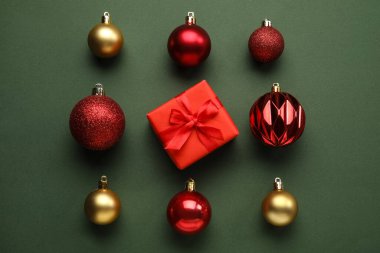 Farklı Noel baloları ve yeşil arka planda hediye kutusu.