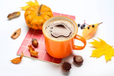 Beyaz arka planda bir fincan kahve, balkabağı, defter ve sonbahar yapraklı kompozisyon