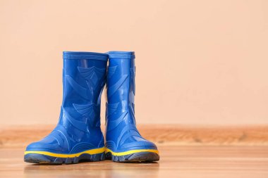 Renkli duvarın yanında bir çift mavi lastik bot.