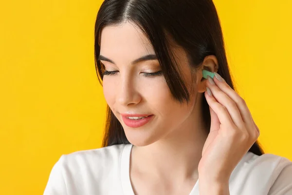 Pretty Young Woman Putting Blue Ear Plug Yellow Background Closeup — Stock Photo, Image