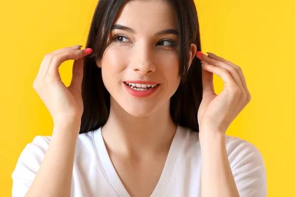 Hübsche Junge Frau Steckt Rosa Ohrstöpsel Auf Gelbem Hintergrund — Stockfoto