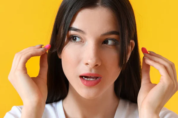 Surprised Young Woman Pink Ear Plugs Yellow Background — Stock Photo, Image