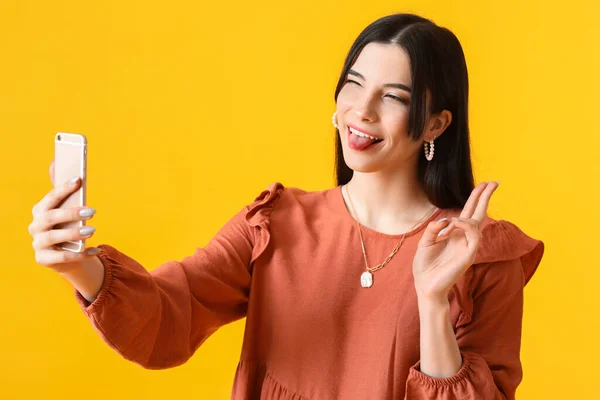 Funny Young Woman Taking Selfie Showing Victory Gesture Yellow Background — Stock Photo, Image