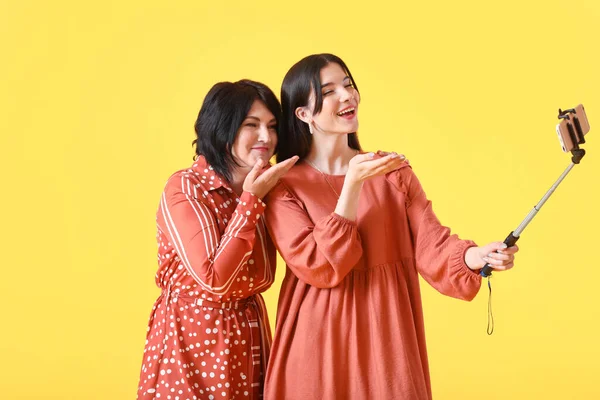 Young Woman Her Mother Taking Selfie Blowing Kiss Yellow Background — Stock Photo, Image