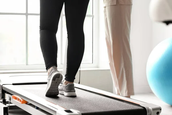 Mature woman training on treadmill in rehabilitation center