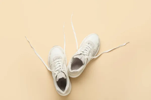 Sportive shoes with untied laces on color background